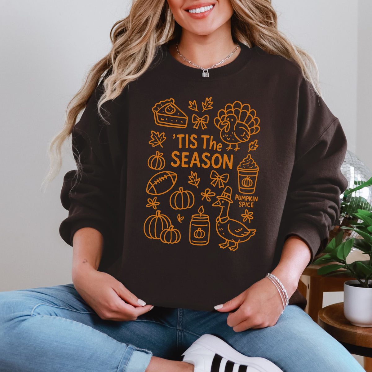 Woman wearing a Dark Chocolate ’Tis the Season Thanksgiving sweatshirt with orange doodle artwork