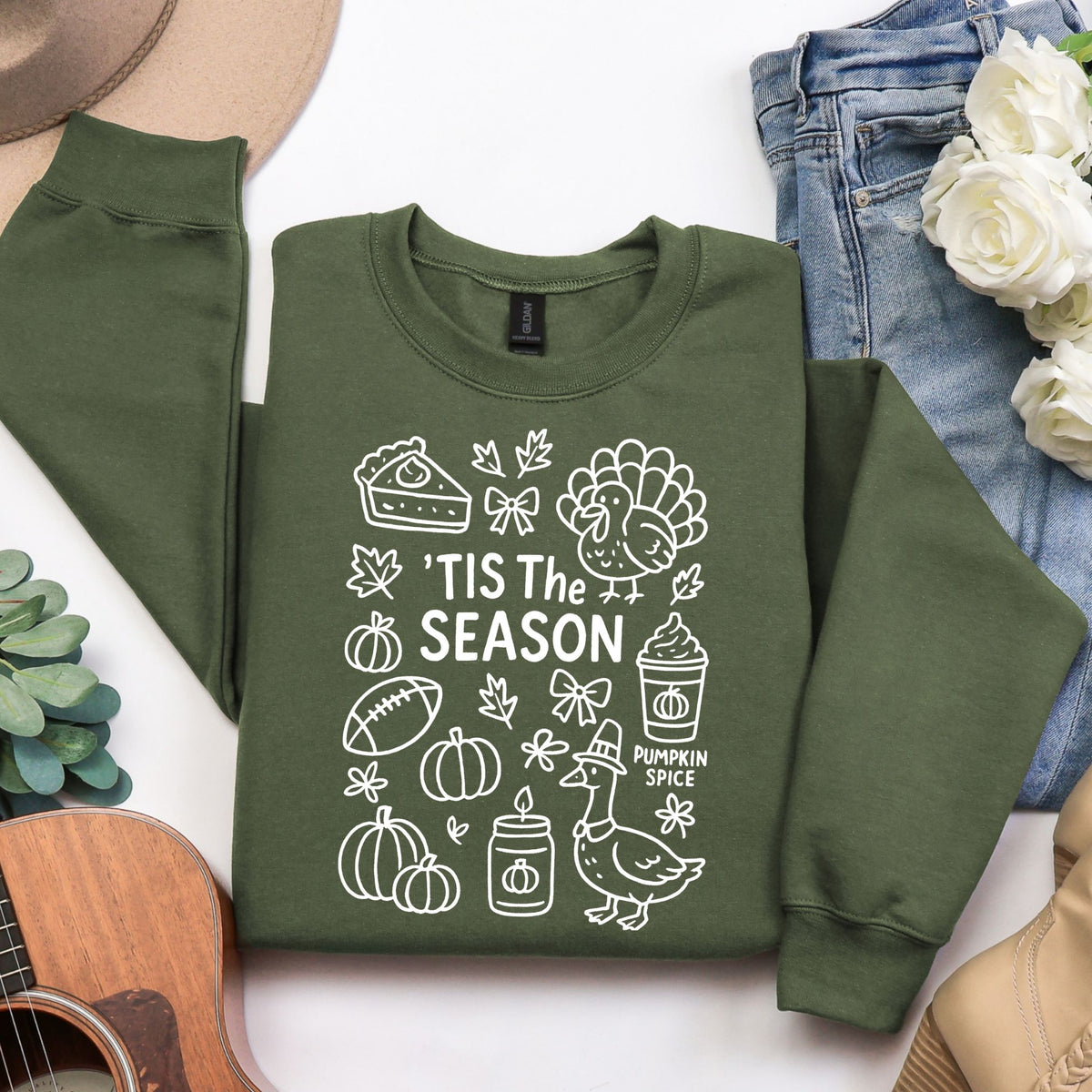 Woman wearing a Military Green 'Tis the Season Thanksgiving sweatshirt with white doodle artwork.