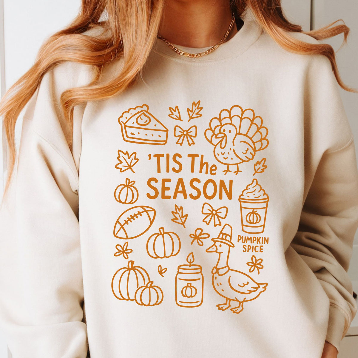 Woman wearing a Natural ’Tis the Season Thanksgiving sweatshirt with orange doodle artwork