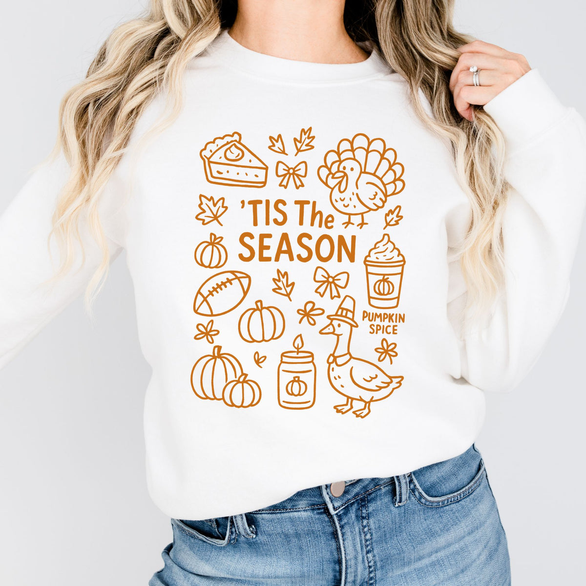 Woman wearing a White ’Tis the Season Thanksgiving sweatshirt with orange doodle artwork