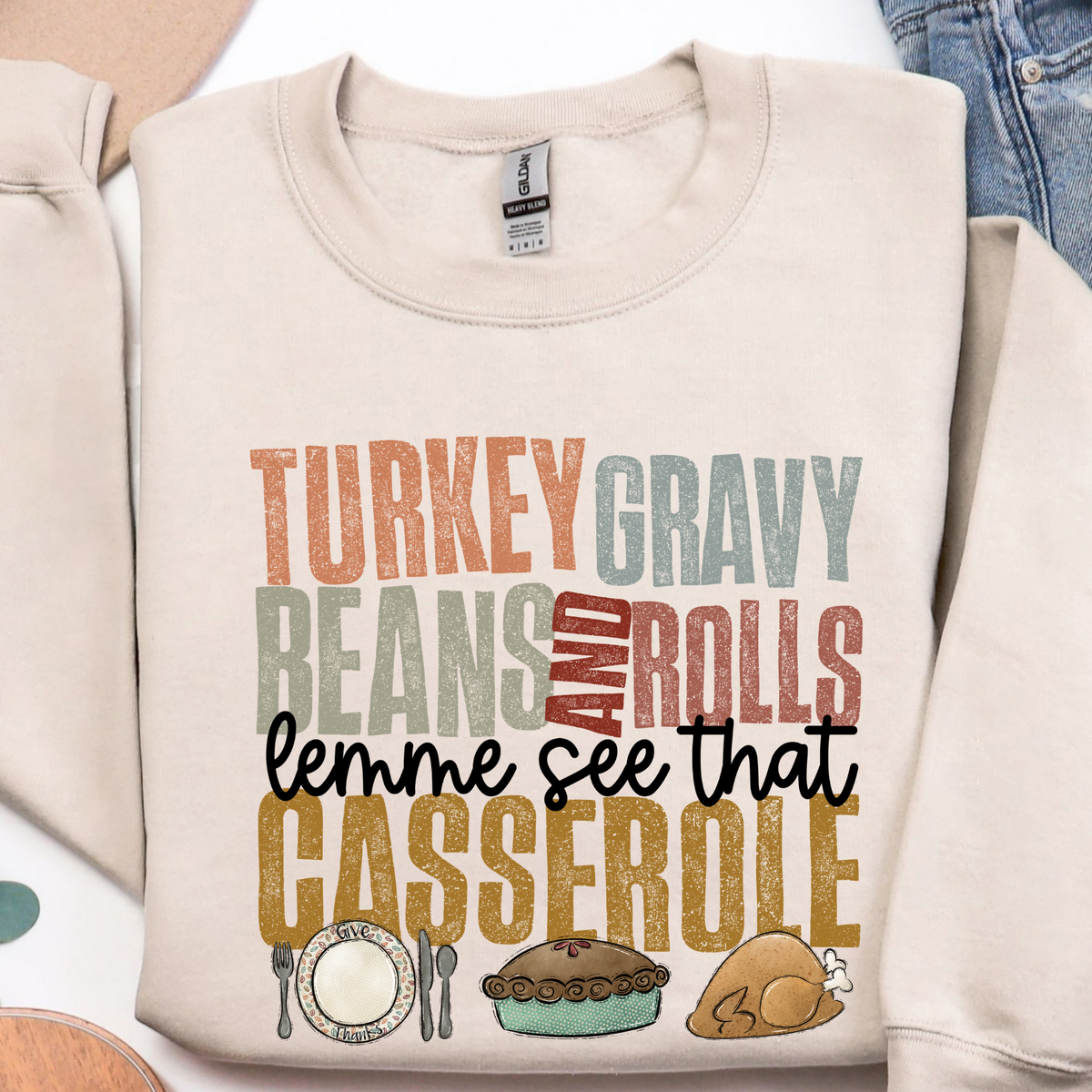 Flat lay of Sand Thanksgiving sweatshirt with turkey, gravy, beans, rolls and casserole design