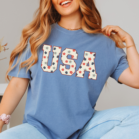 Woman wearing a blue jean T-shirt with a floral USA collegiate design.