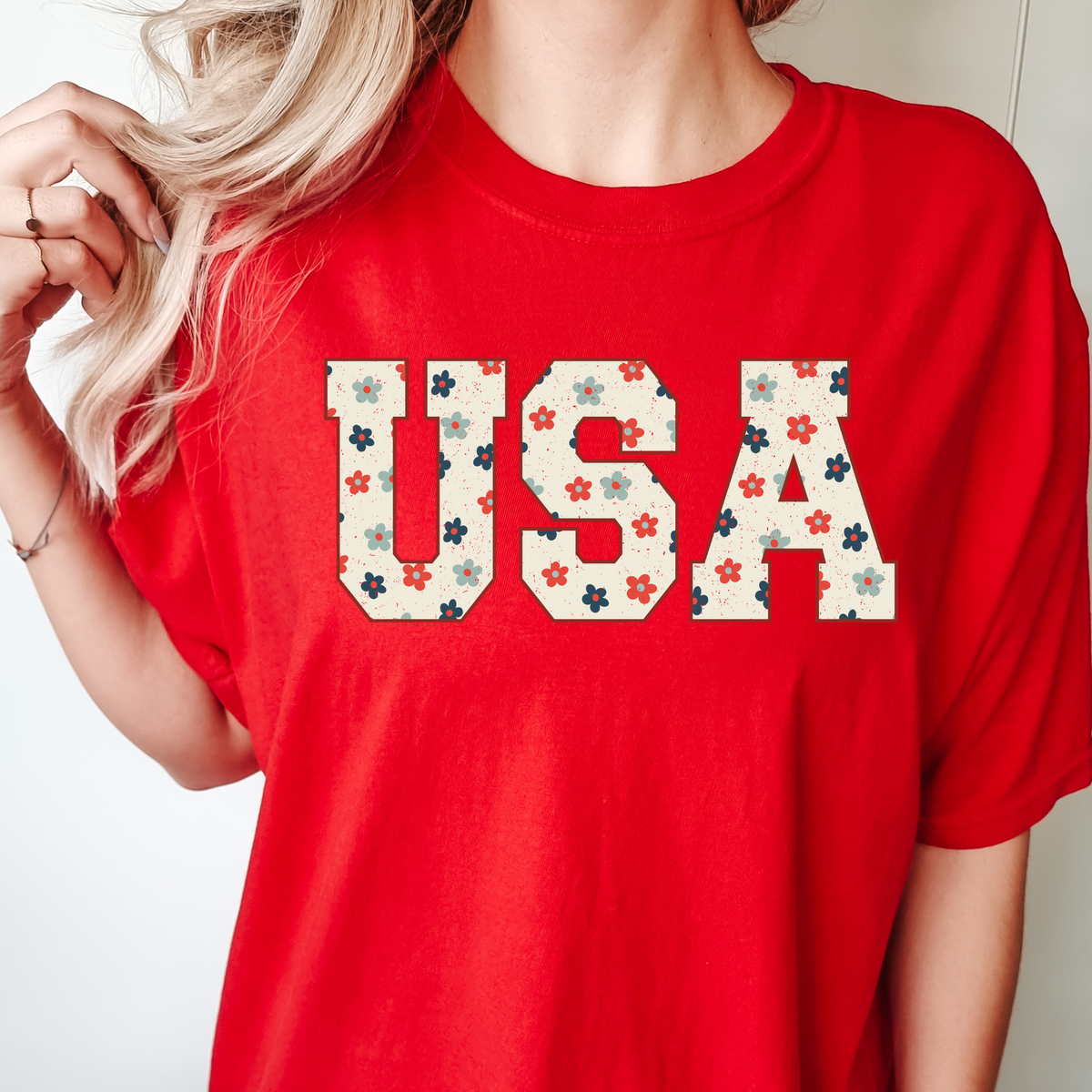 Woman wearing a red T-shirt with a floral USA collegiate design.